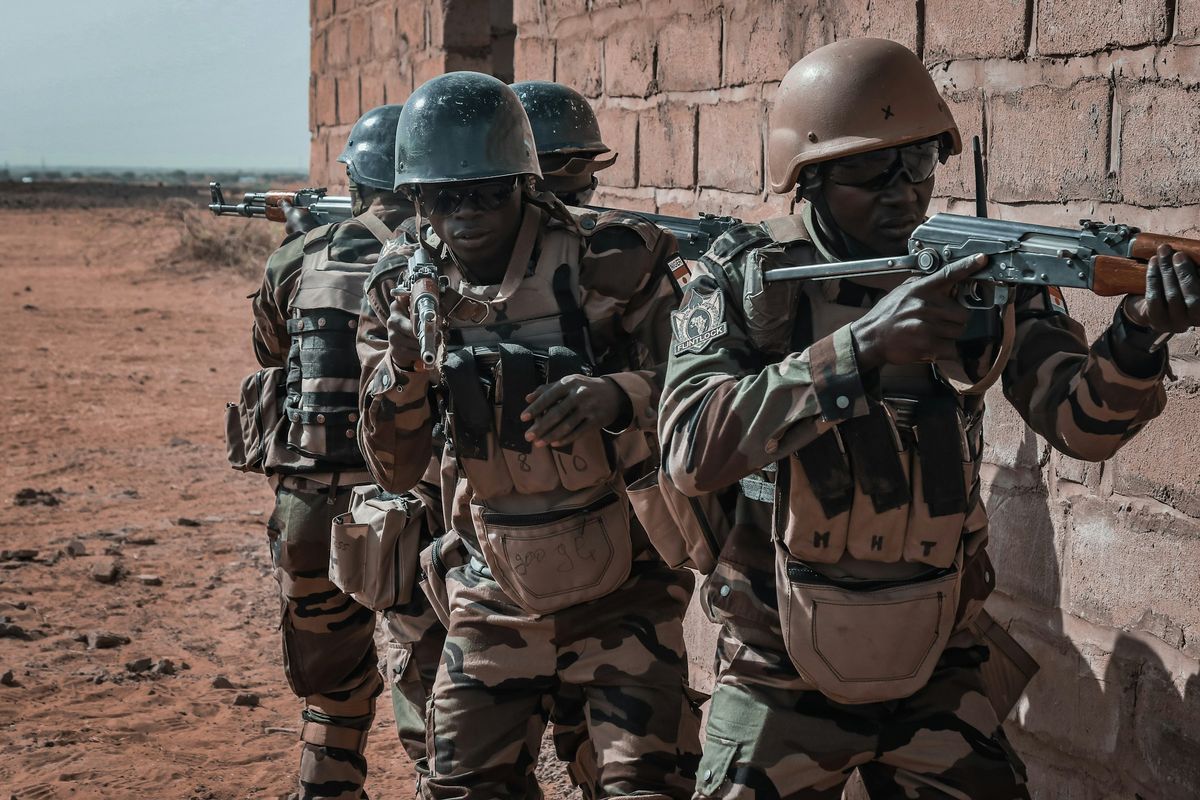 Soldiers advancing along a wall with rifles raised