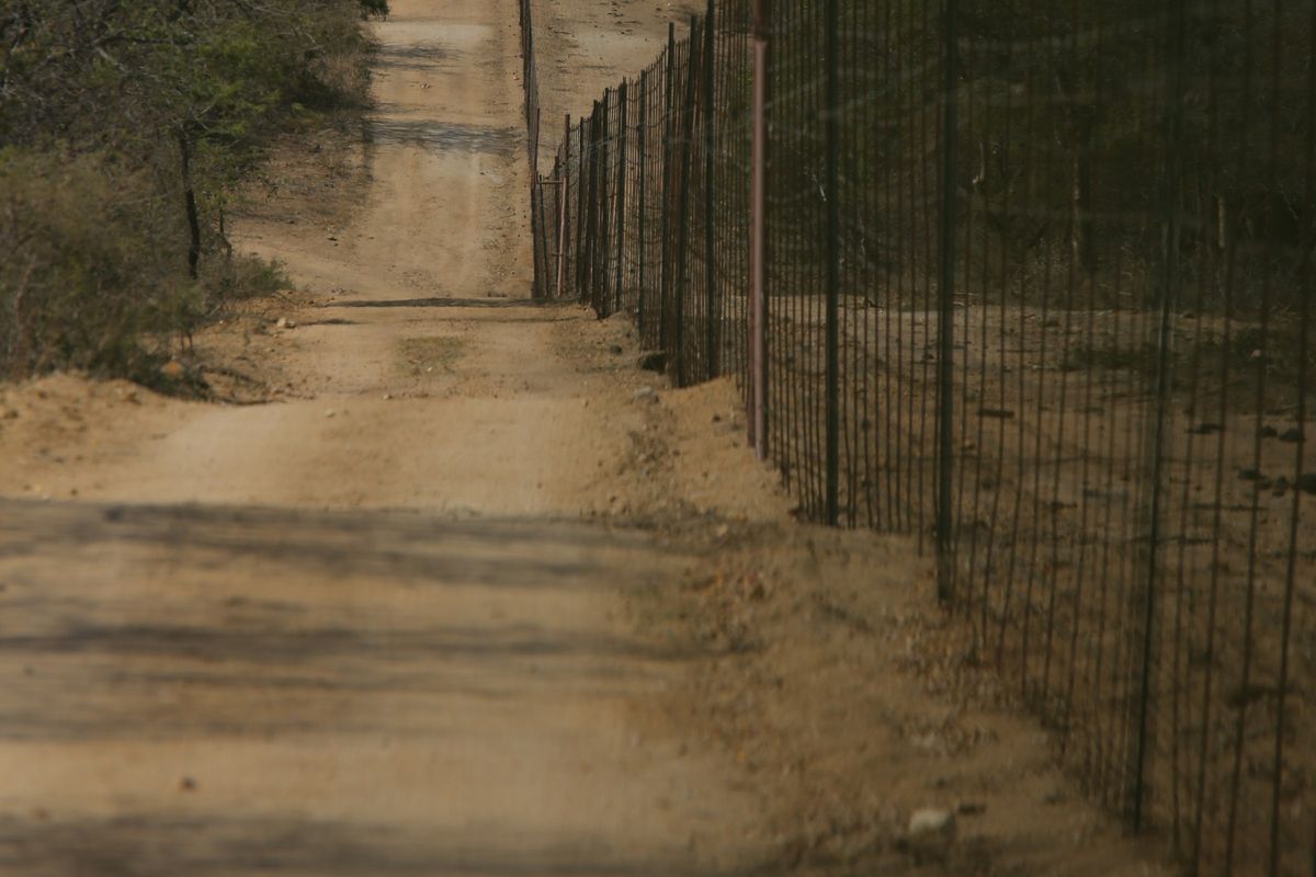 A dirt track running beside a long boundary fence
