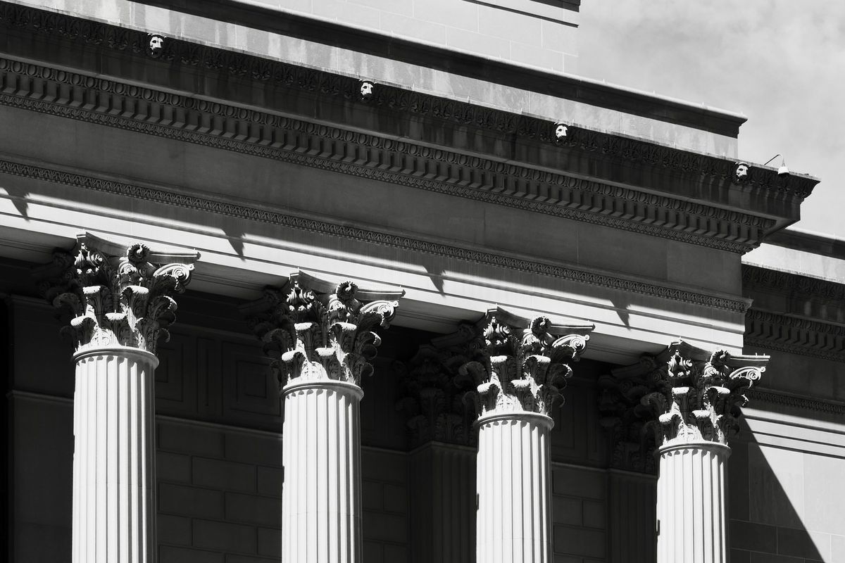 The columned facade of a public building, in black and white