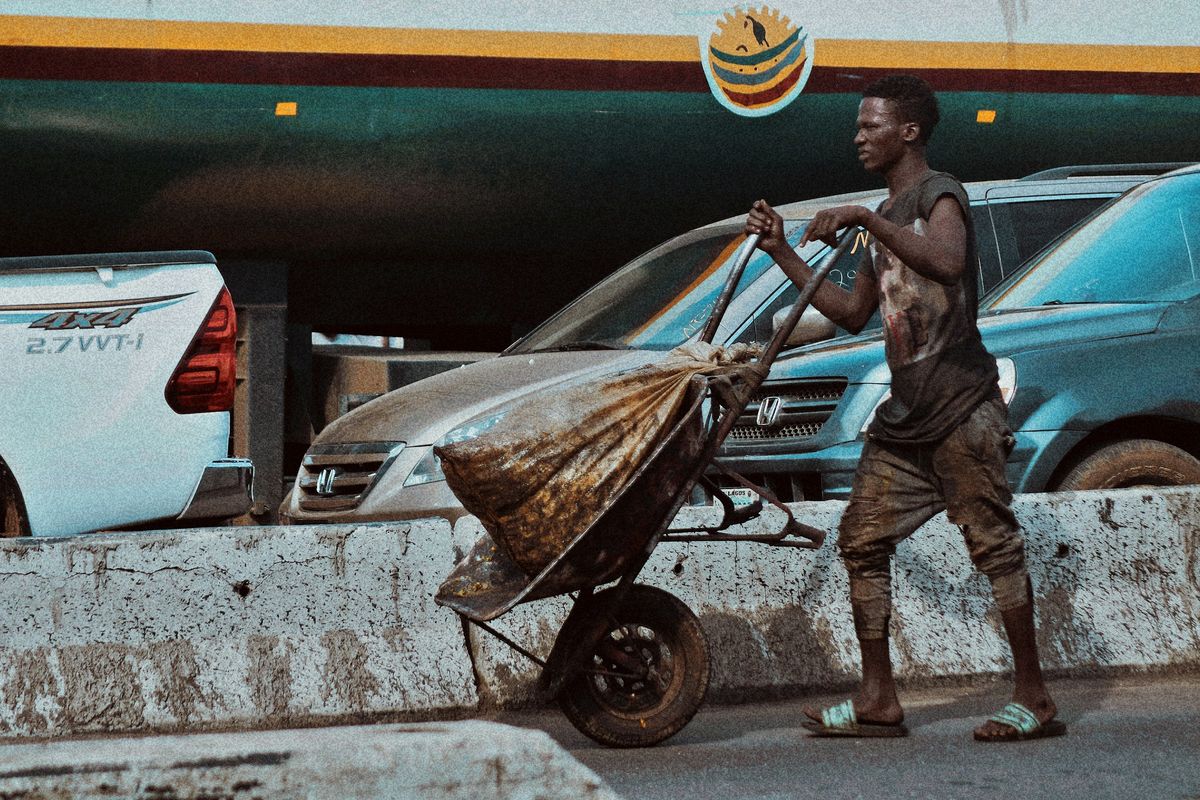 A porter pushing a cart past cars