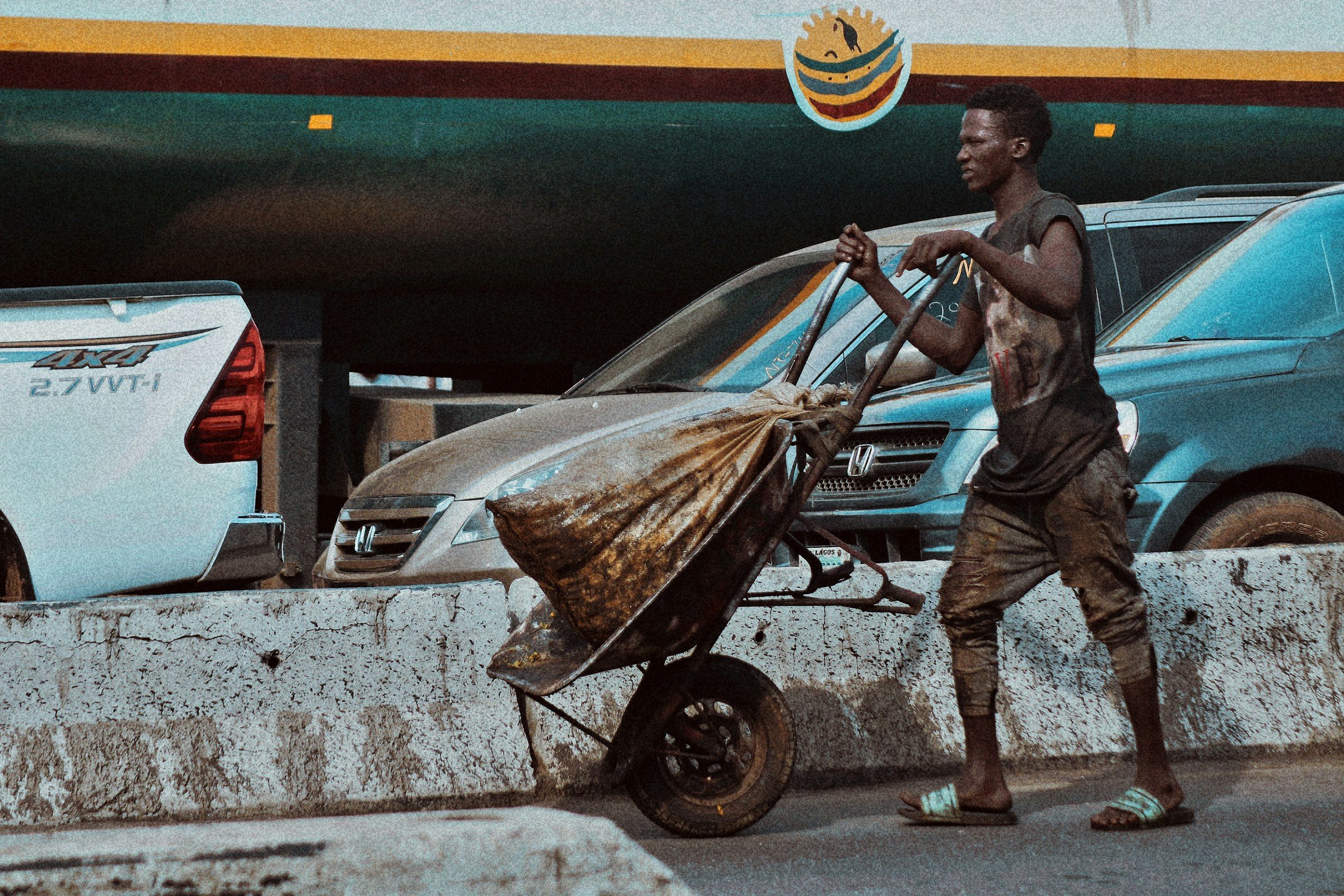 A porter pushing a cart past cars