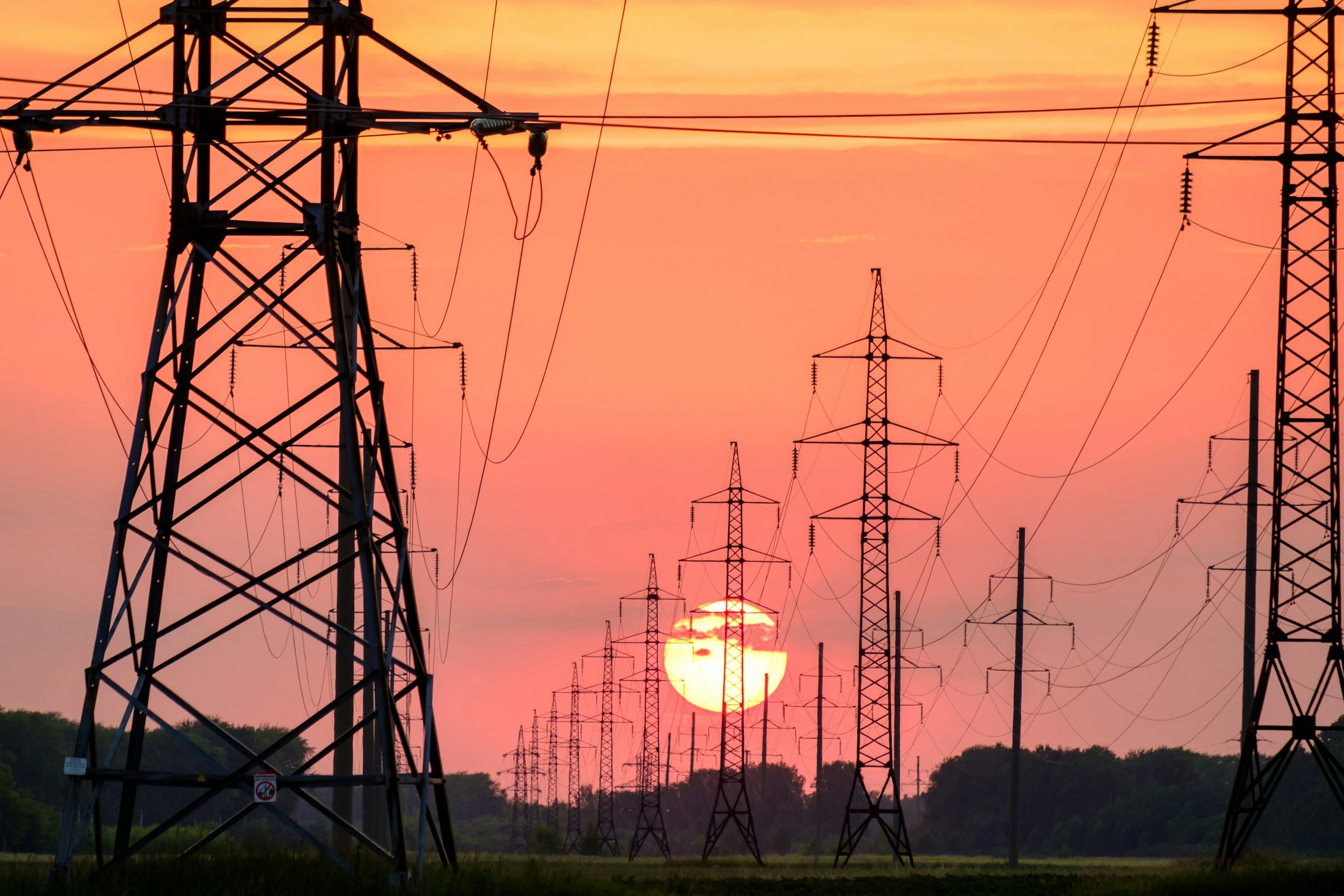 Electricity pylons silhouetted at sunset