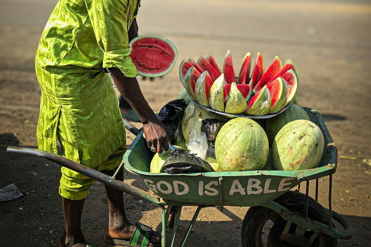 A man pushing a wheelbarrow of watermelons