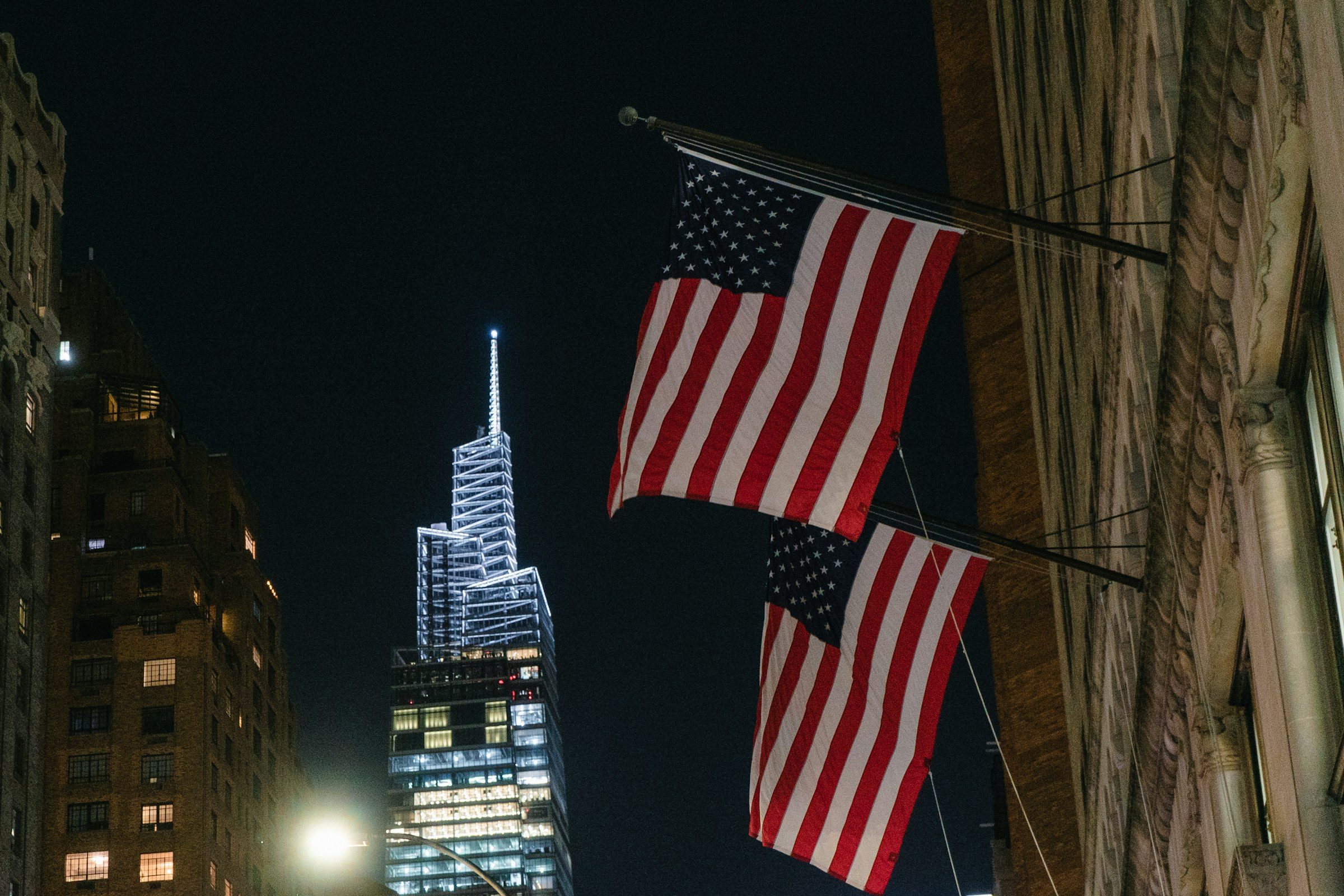 United States flags flying from a building at night