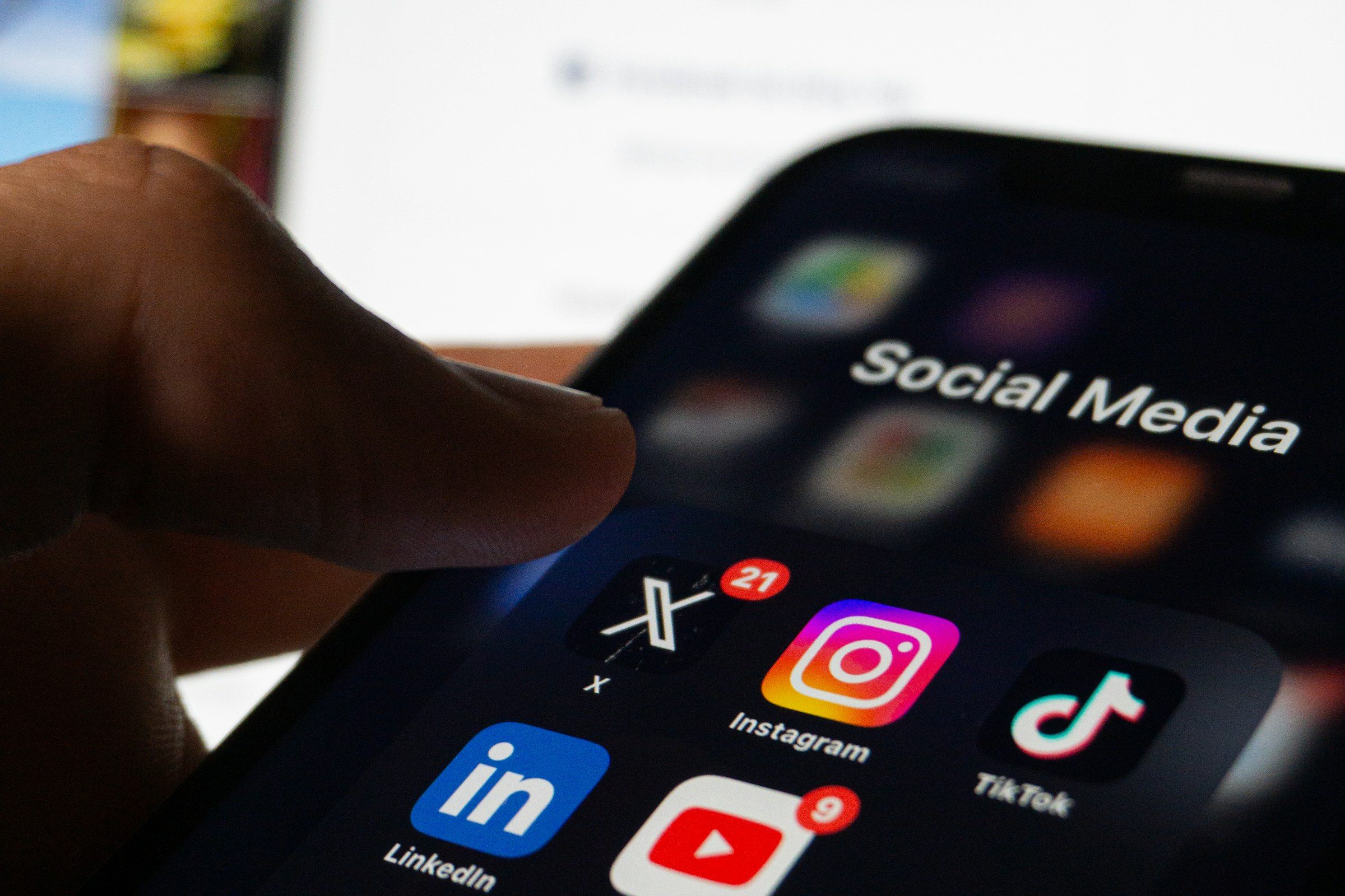 A hand holding a smartphone showing social media applications
