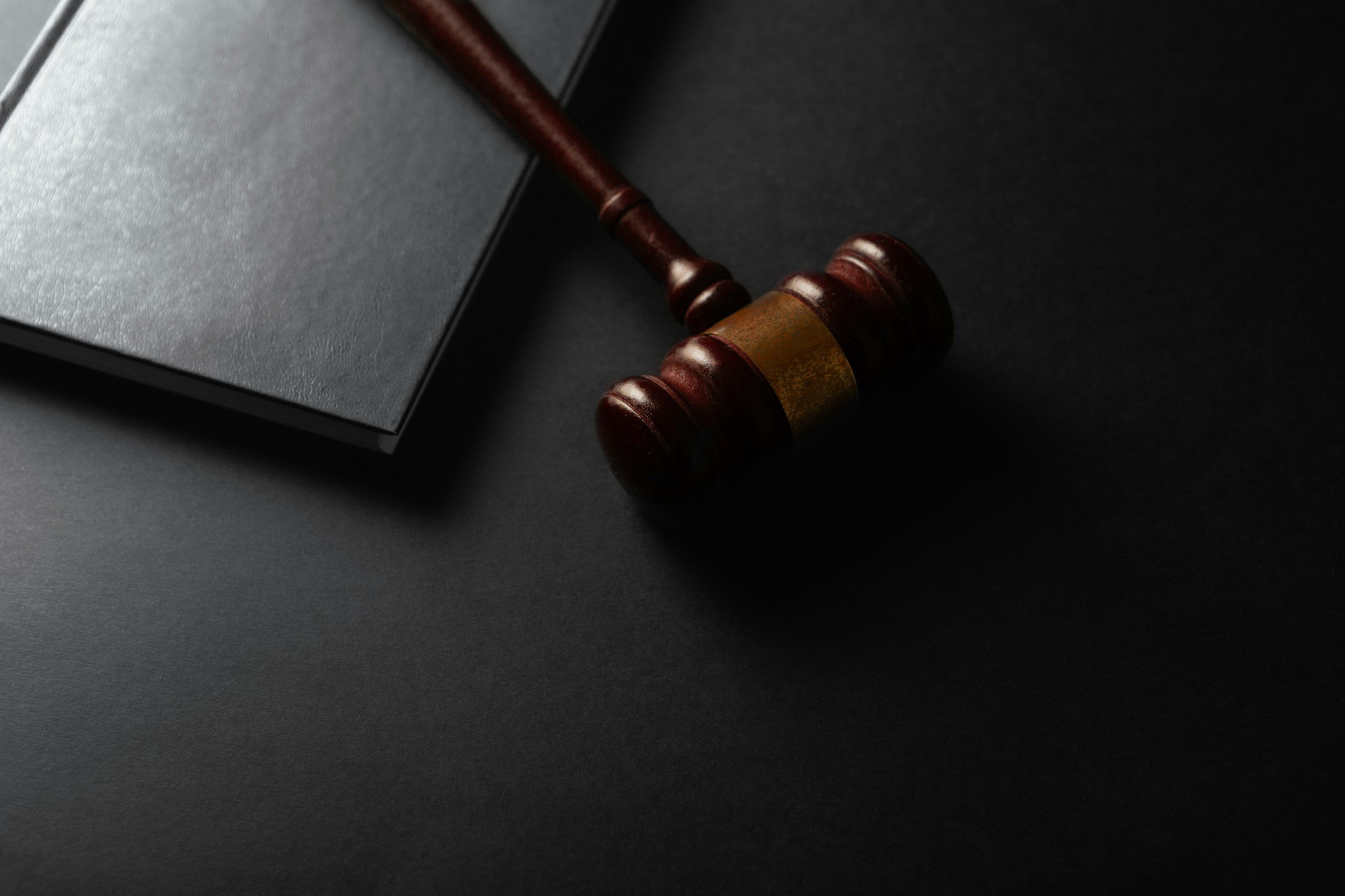 A wooden gavel resting beside a book on a dark surface
