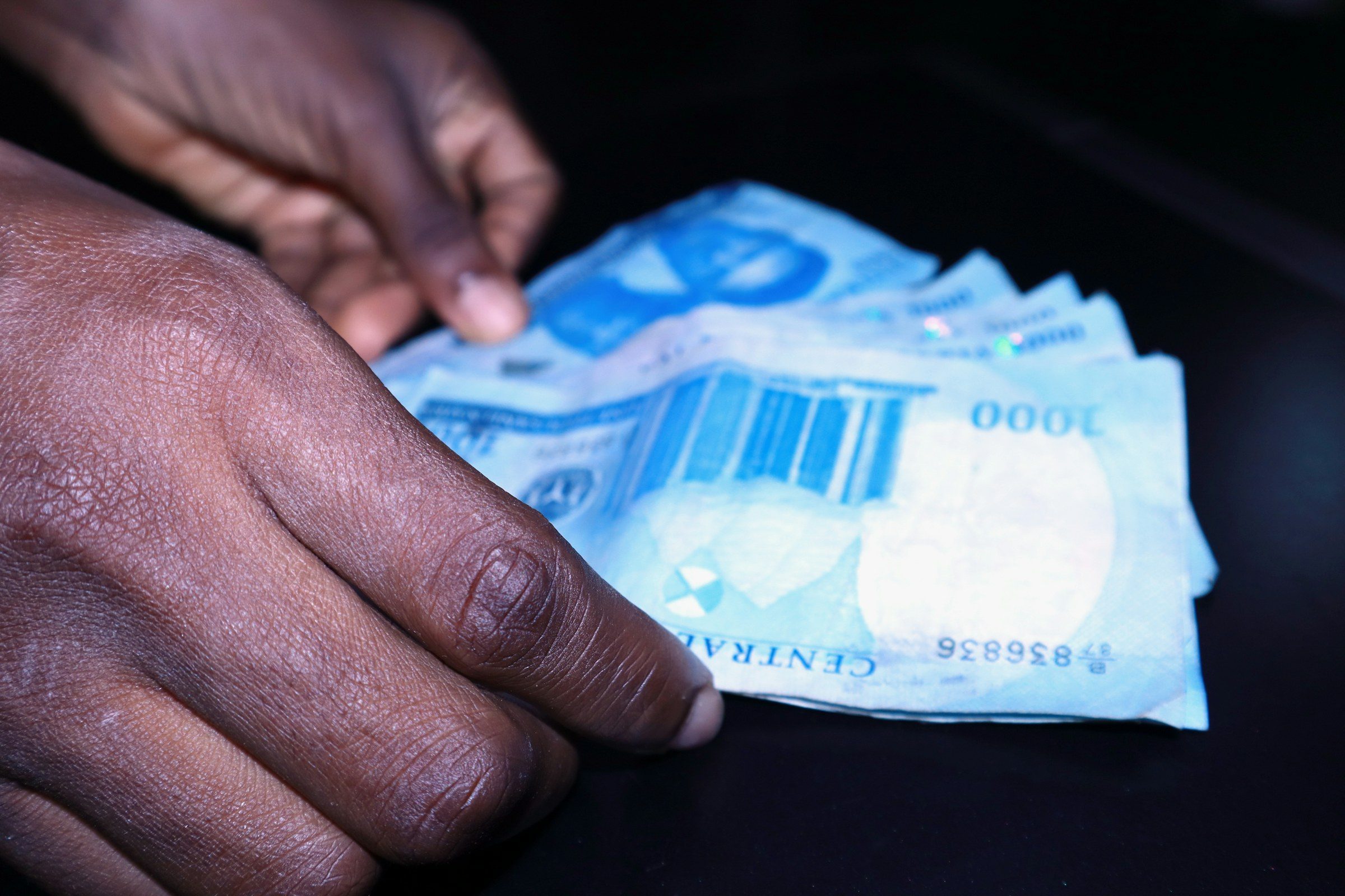 A hand counting one-thousand-naira notes